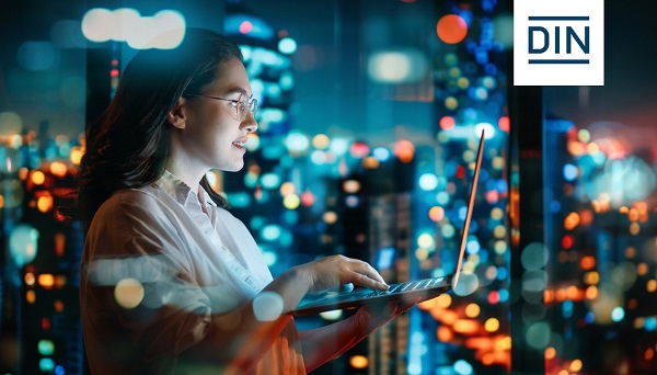 Frau am Laptop vor Fenstern mit Lichtern einer Skyline